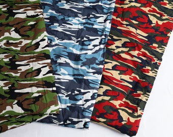 May include: Three fabric samples with camouflage patterns. One features green, brown, and white; another, blue and white; and the third, red, green, and tan. The fabrics are folded, showcasing the repeating designs.