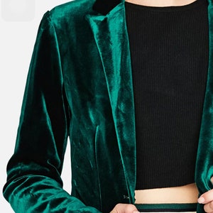 Op de afbeelding: Een donkergroen fluwelen blazer met een zwarte kraag. De blazer heeft een enkele knoopsluiting en lange mouwen.