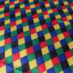 May include: A colorful fabric with a repeating pattern of squares in red, yellow, green, blue, and black. The squares are arranged in a diagonal checkerboard design, creating a vibrant and eye-catching textile.