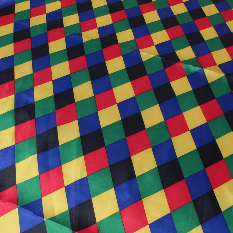 May include: A colorful fabric with a repeating pattern of squares in red, yellow, green, blue, and black. The squares are arranged in a diagonal checkerboard design, creating a vibrant and eye-catching textile.
