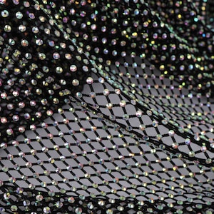 Peut inclure: Tissu en maille noire avec des strass irisés. La maille est un motif en losange.
