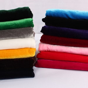 Op de afbeelding: Een stapel van 10 verschillende gekleurde fluwelen stofstalen. De kleuren zijn groen, grijs, wit, geel, bruin, zwart, blauw, paars, rood en roze.