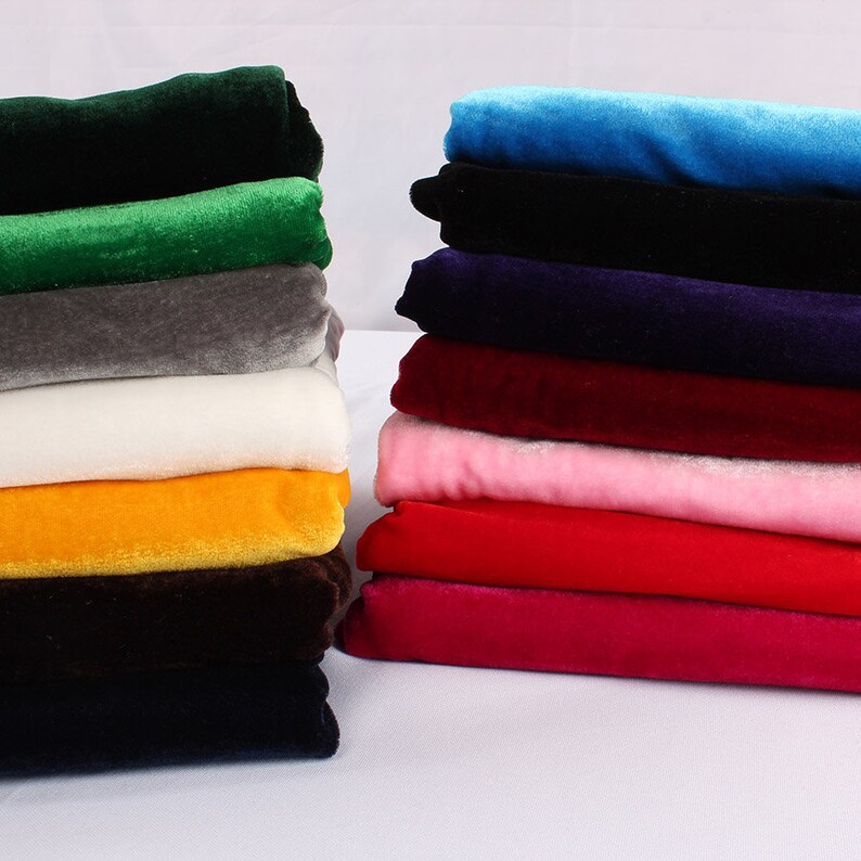Op de afbeelding: Een stapel van 10 verschillende gekleurde fluwelen stofstalen. De kleuren zijn groen, grijs, wit, geel, bruin, zwart, blauw, paars, rood en roze.