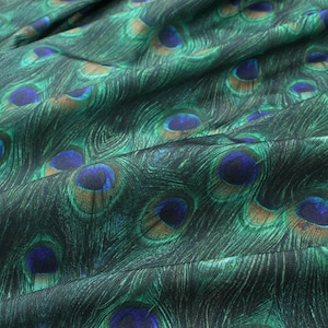 May include: Green fabric with a peacock feather pattern. The fabric has a subtle sheen and is soft to the touch.