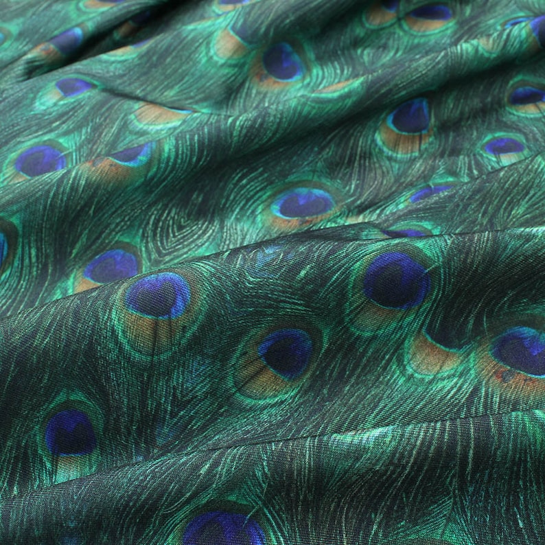 May include: Green fabric with a peacock feather pattern. The fabric has a subtle sheen and is soft to the touch.