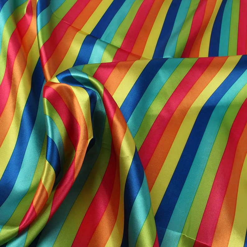 May include: A vibrant fabric with diagonal stripes in a rainbow of colors: red, orange, yellow, green, blue, and teal. The fabric has a shiny, satin-like finish, with folds and soft curves.
