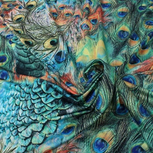 May include: A fabric with a peacock feather print. The fabric is a mix of blue, green, and orange colors. The feathers are arranged in a random pattern.