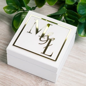 Può includere: Scatola per anelli quadrata bianca con bordo dorato e le iniziali "M&L" in lettere dorate.