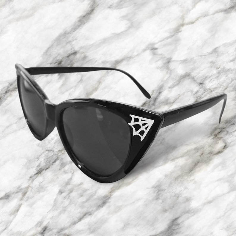 May include: Black cat eye sunglasses with a silver spider web design on the side.