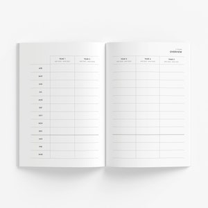 May include: Open white notebook with a minimalist design. The left page lists months from April to March. The right page is labeled "5 Years Overview" and has columns for five years. The notebook is open on a white surface.
