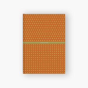 May include: Orange notebook with a yellow polka dot pattern and the name "Kamila Patel" printed on the front.