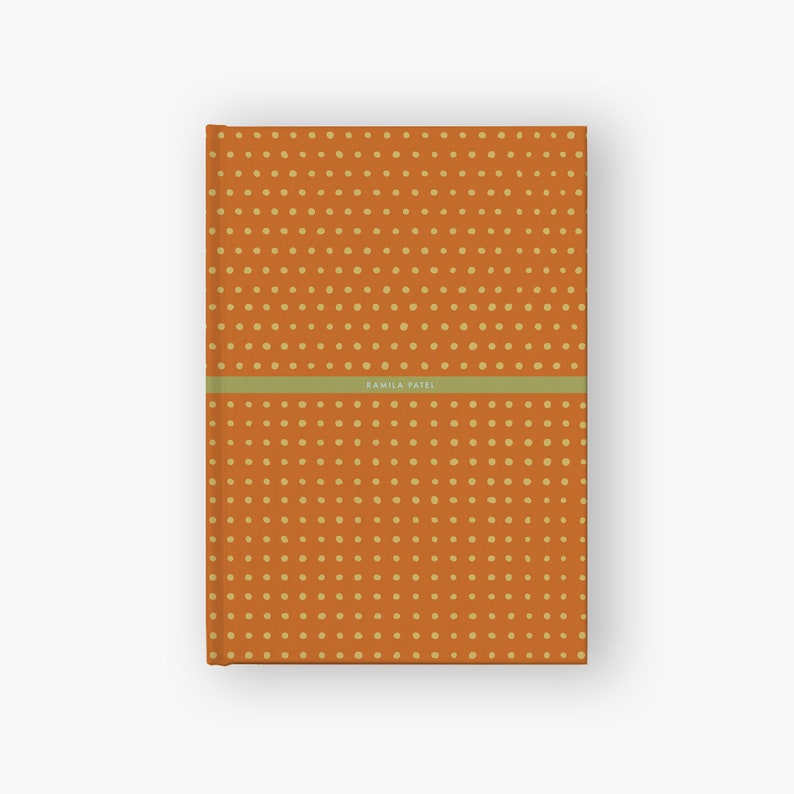 May include: Orange notebook with a yellow polka dot pattern and the name "Kamila Patel" printed on the front.