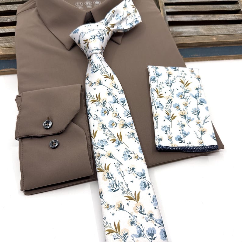 May include: A brown dress shirt with a white and blue floral patterned tie and a matching pocket square.