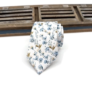 May include: A white necktie with a blue and brown floral pattern.