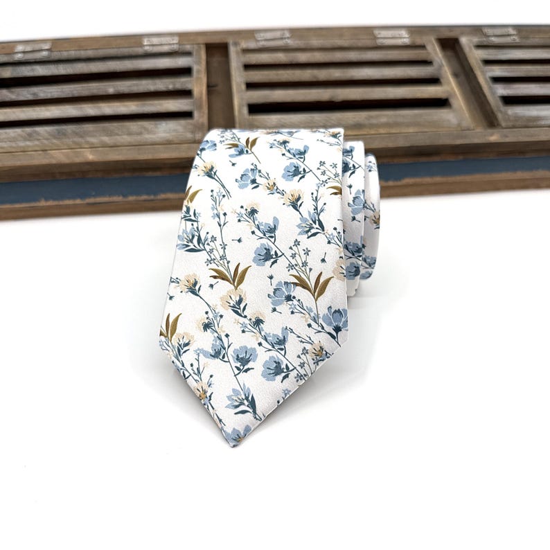 May include: A white necktie with a blue and brown floral pattern.