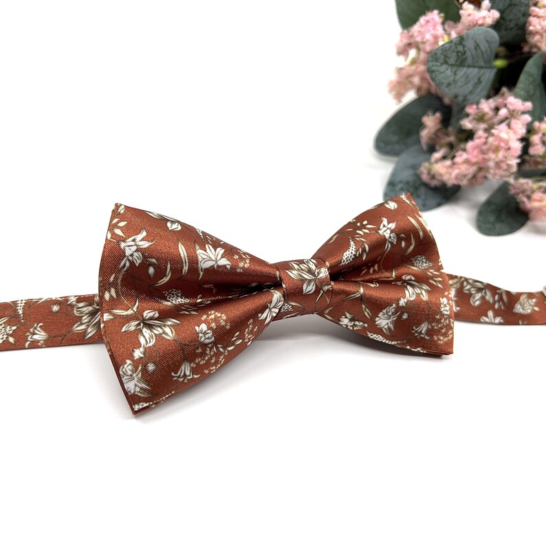 Peut inclure: Un n&oelig;ud papillon marron avec un motif floral blanc.