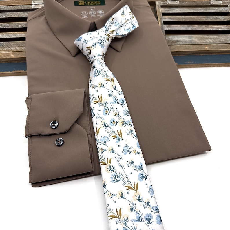 May include: A brown dress shirt with a white tie featuring a blue and brown floral pattern.
