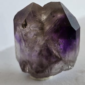 May include: A white ceramic mug with a black handle and the text "But first, coffee" in a handwritten style. The mug is on a white surface. The mug is approximately 4 inches tall.