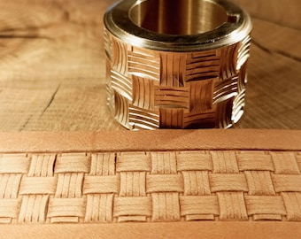 May include: A brass leather stamping tool with a basket weave pattern. The tool is cylindrical with a detailed woven design. A strip of leather with a matching basket weave pattern is in the foreground.