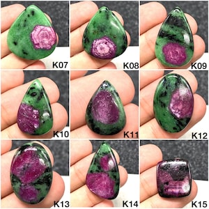 Könnte beinhalten: Eine Sammlung polierter Rubin-in-Zoisit-Edelsteine in verschiedenen Formen. Die Edelsteine weisen eine lebendige Mischung aus grünem und schwarzem Zoisit mit auffälligen Rubin-Einschlüssen in Rosa- und Rottönen auf. Jeder Stein ist einzigartig.