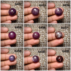 Può includere: Una collezione di nove pietre preziose cabochon rotonde e levigate in varie tonalità di viola, magenta e rosso intenso. Ogni pietra è etichettata con un numero identificativo univoco da 6452 a 6460, mostrando motivi e texture naturali distinti.