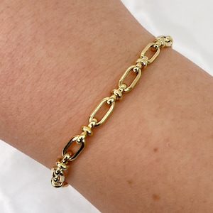 May include: A gold chain bracelet with a thick, chunky link design. The bracelet is made of metal and has a polished finish.