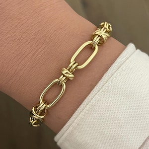 May include: A gold chain bracelet with a thick, twisted link design.