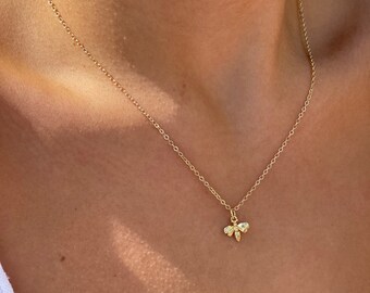 May include: A gold chain necklace with a small bee pendant. The bee is made of gold and has a textured surface.
