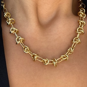Peut inclure: Un collier en cha&icirc;ne dor&eacute;e avec un motif nou&eacute;. La cha&icirc;ne est compos&eacute;e de maillons &eacute;pais et ronds qui sont torsad&eacute;s ensemble pour cr&eacute;er un motif nou&eacute;.