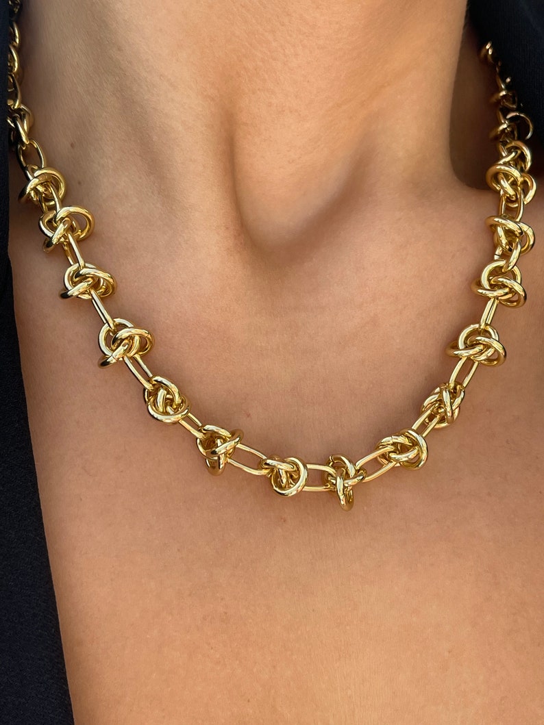 Peut inclure: Un collier en cha&icirc;ne dor&eacute;e avec un motif nou&eacute;. La cha&icirc;ne est compos&eacute;e de maillons &eacute;pais et ronds qui sont torsad&eacute;s ensemble pour cr&eacute;er un motif nou&eacute;.