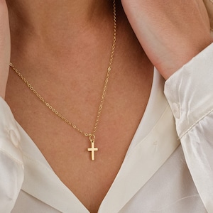 May include: A gold chain necklace with a small gold cross pendant.