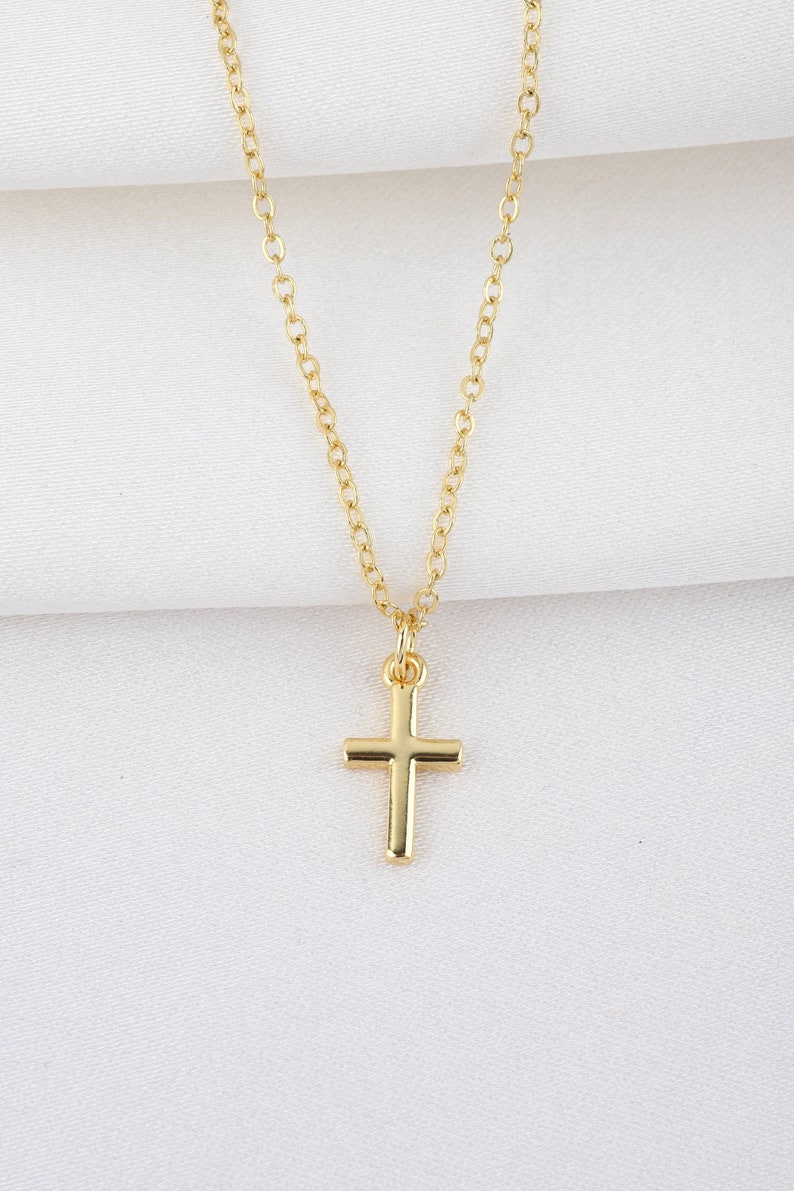 May include: A gold chain necklace with a small gold cross pendant.