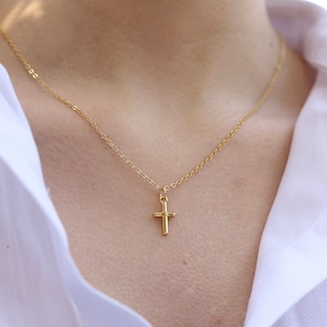 May include: A gold chain necklace with a small gold cross pendant.