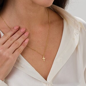 May include: A gold chain necklace with a small gold cross pendant.