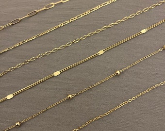 May include: A set of six gold chains of varying lengths and styles, including a chain with small round beads, a chain with oval links, and a chain with a delicate, patterned design.