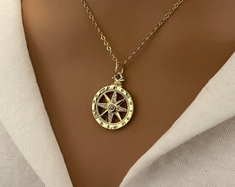May include: A gold chain necklace with a compass pendant featuring a star design with clear rhinestones. The compass face has the letters N, S, E, and W around the edge.