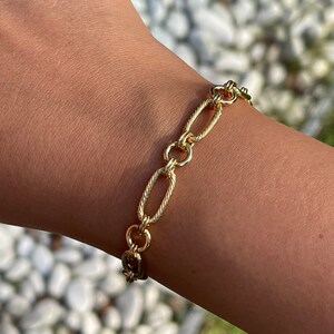 May include: A gold chain bracelet with oval links. The chain is twisted and has a polished finish.