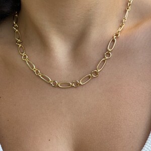 May include: A gold chain necklace with a delicate, oval-shaped link design.