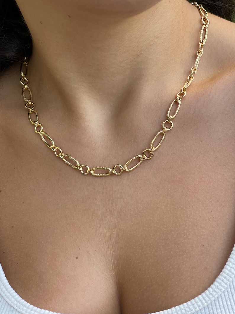 May include: A gold chain necklace with a delicate, oval-shaped link design.