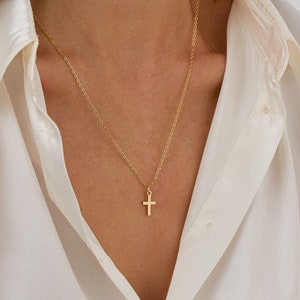 May include: A gold chain necklace with a small gold cross pendant.