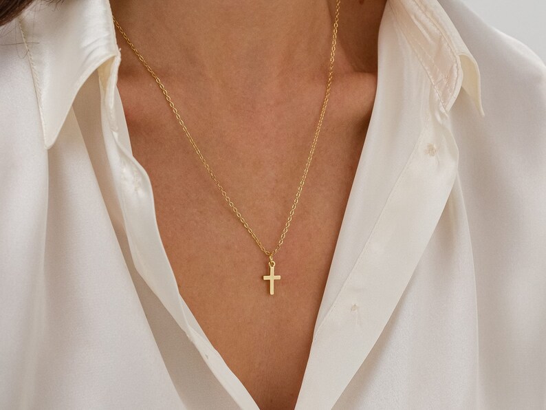 May include: A gold chain necklace with a small gold cross pendant.