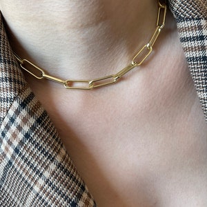 May include: A gold chain necklace with a simple, linked design. The chain is made of thick, oval-shaped links.