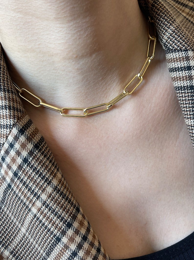 May include: A gold chain necklace with a simple, linked design. The chain is made of thick, oval-shaped links.