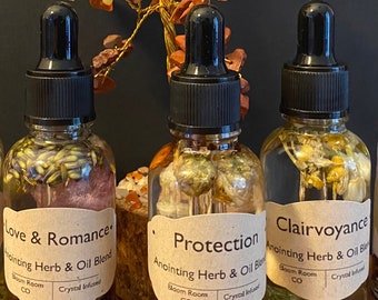 May include: Three glass bottles with black dropper tops filled with herbs and crystals. The bottles are labeled "Love & Romance", "Protection", and "Clairvoyance". Each bottle is labeled "Anointing Herb & Oil Blend", "Bloom Room CO", and "Crystal Infused".