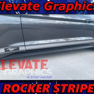 May include: A gray Ford Mustang with a black and white rocker stripe decal. The decal features the Ford Mustang logo. The decal is applied to the side of the car, just below the doors. The text "Elevate Graphics" is visible in the top left corner of the image. The text "ROCKER STRIPE" is visible in the bottom center of the image.