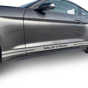 May include: A grey Ford Mustang with silver and black side stripes and the word "MUSTANG" in black lettering on the side of the car.