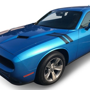 May include: A blue Dodge Challenger with black racing stripes on the side of the car. The car has a black front grille and black wheels.