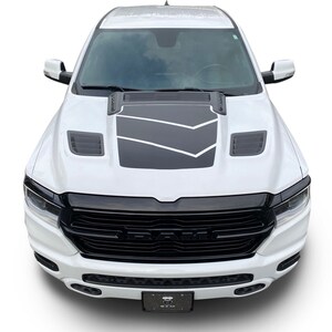 May include: White pickup truck with a black grille and black hood scoop. The truck has a black and grey graphic on the hood.