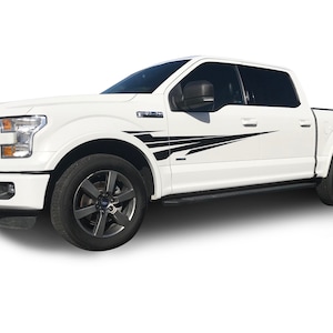 Puede incluir: Camioneta Ford F-150 blanca con rayas de carreras negras en los lados. La camioneta tiene una parrilla negra y ruedas negras.