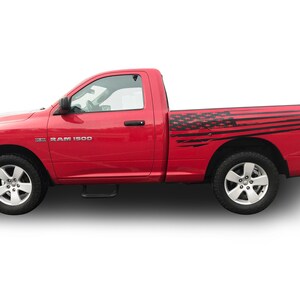 May include: A red Dodge Ram 1500 pickup truck with a black and white American flag decal on the side of the load bed.